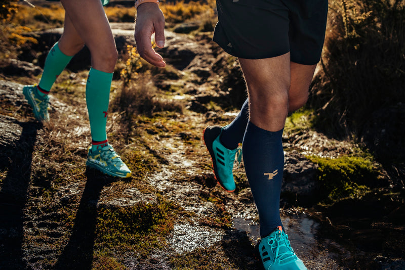 Hombre y mujer piernas corriendo por un sendero con ropa de Fyke.