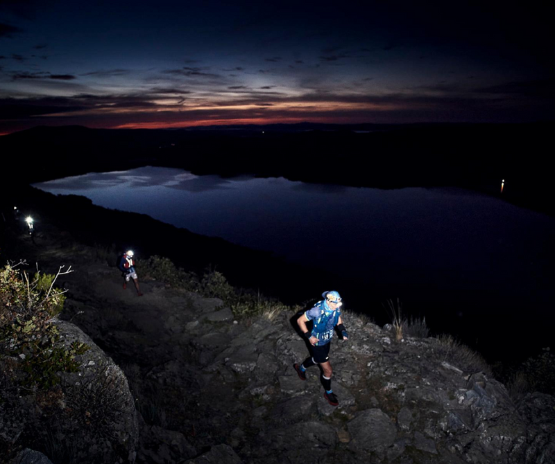 Corredores en una carrera nocturna de trail running con el bello paisaje de un lago.