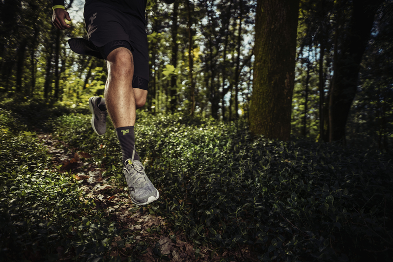 Hombre saltando en medio de un sendero en una zona forestal con equipo deportivo Fyke.