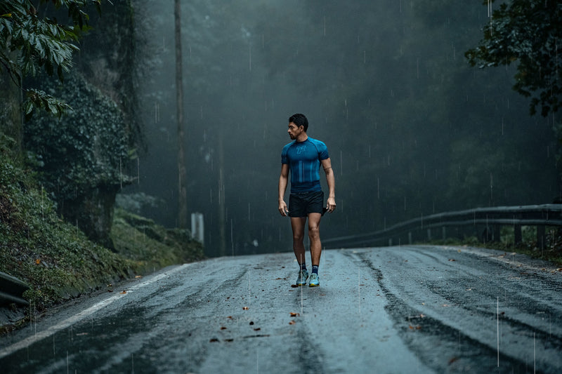 Hombre con ropa deportiva Fyke en un entorno lluvioso.