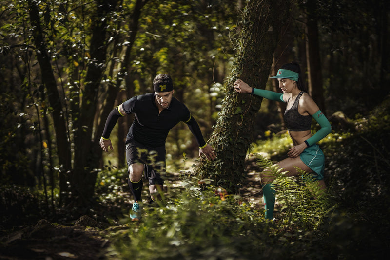 Couple pratiquant la course à pied en forêt et portant des vêtements de sport Fyke.