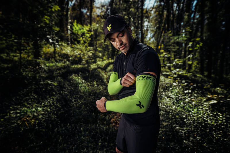 Homme en forêt enfilant son manchon de compression Fyke pour la récupération musculaire.