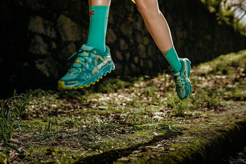 Jambes de femme courant sur un sentier avec des chaussettes Fyke.