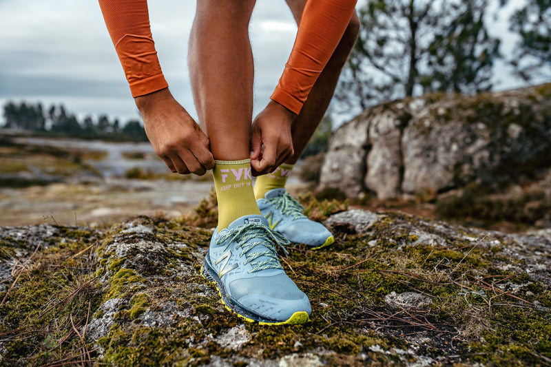 Homme ajustant sa chaussette green Fyke dans la nature