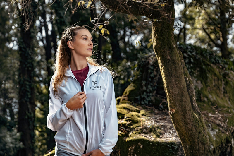 Femme dans un environnement forestier portant une veste de course imperméable Fyke.