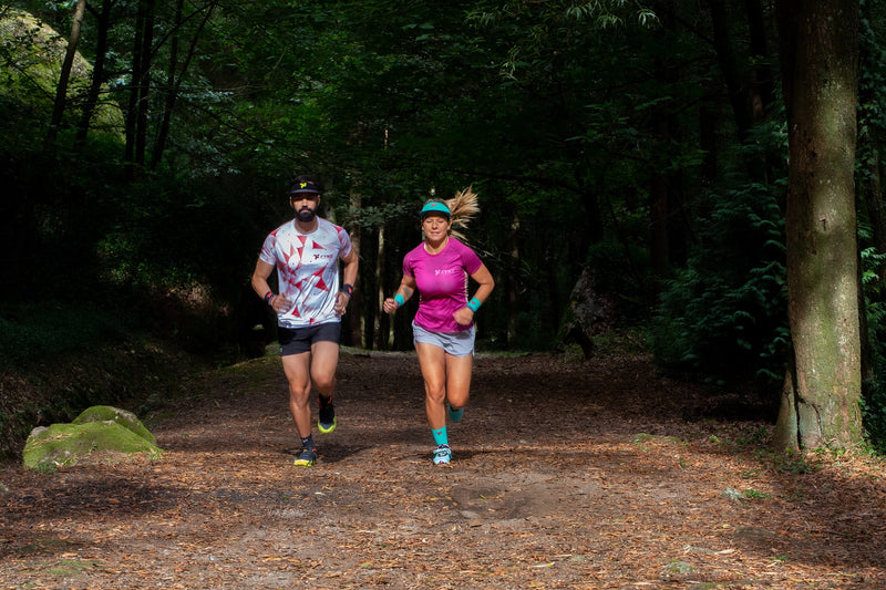 Homem e mulher equipados pela Fyke a praticar trail running em terreno florestal.