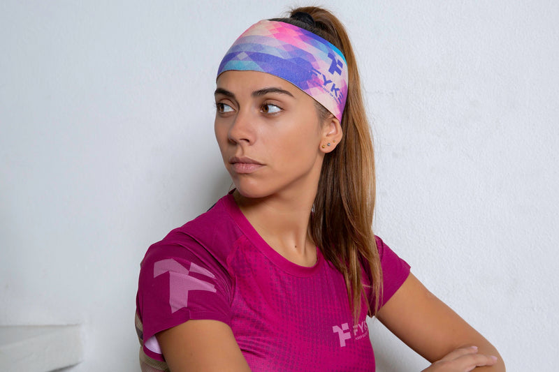 Mulher com uma bandolete desportiva em tons de rosa e blue e uma t-shirt desportiva feminina Fyke cor-de-rosa