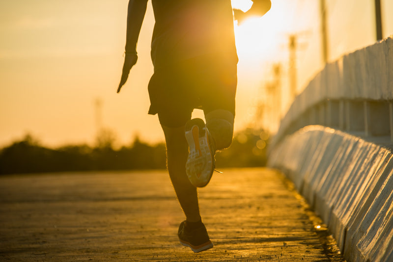 Silhueta de um homem a correr uma maratona ao nascer do sol.